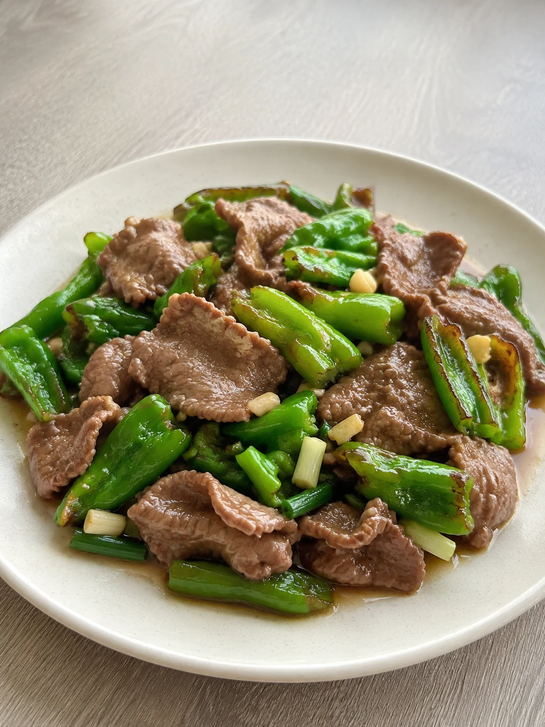 尖椒炒牛肉成品，牛肉薄片与微皱尖椒带有自然油光